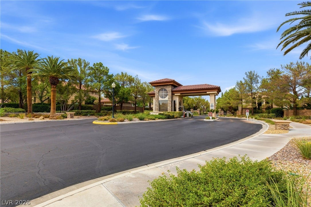10626 San Vercelli Court, Las Vegas, NV 89141 A secure gated entrance welcomes residents with a stone gatehouse and tile roofing.