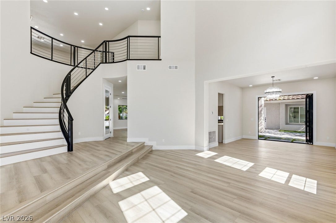 10626 San Vercelli Court, Las Vegas, NV 89141 A striking curved staircase anchors this open-concept layout with towering ceilings and seamless outdoor access.