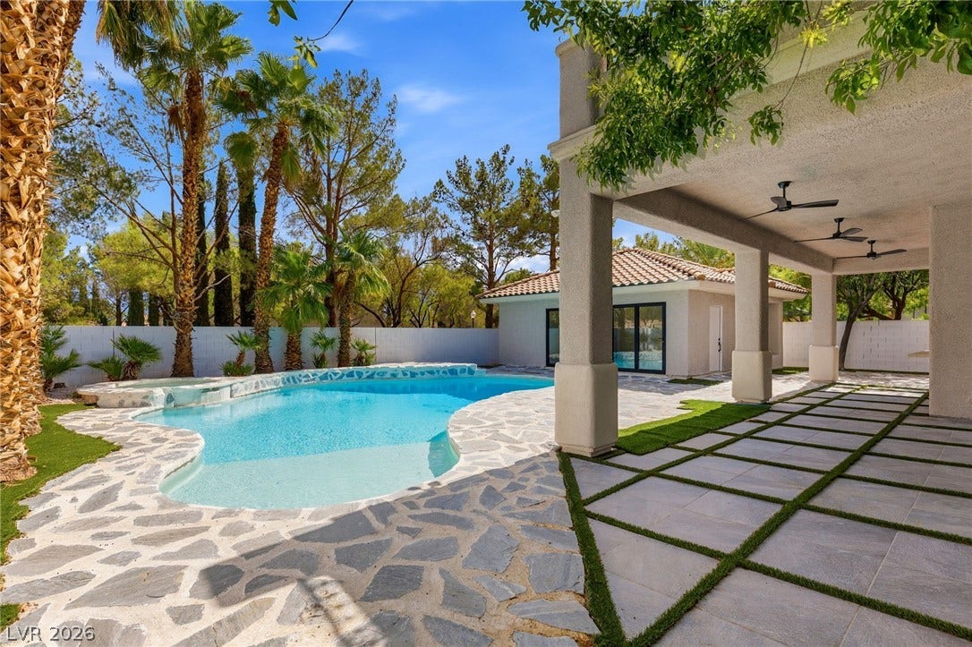 10626 San Vercelli Court, Las Vegas, NV 89141 A spacious covered terrace overlooks a resort-style swimming pool surrounded by mature palm trees.