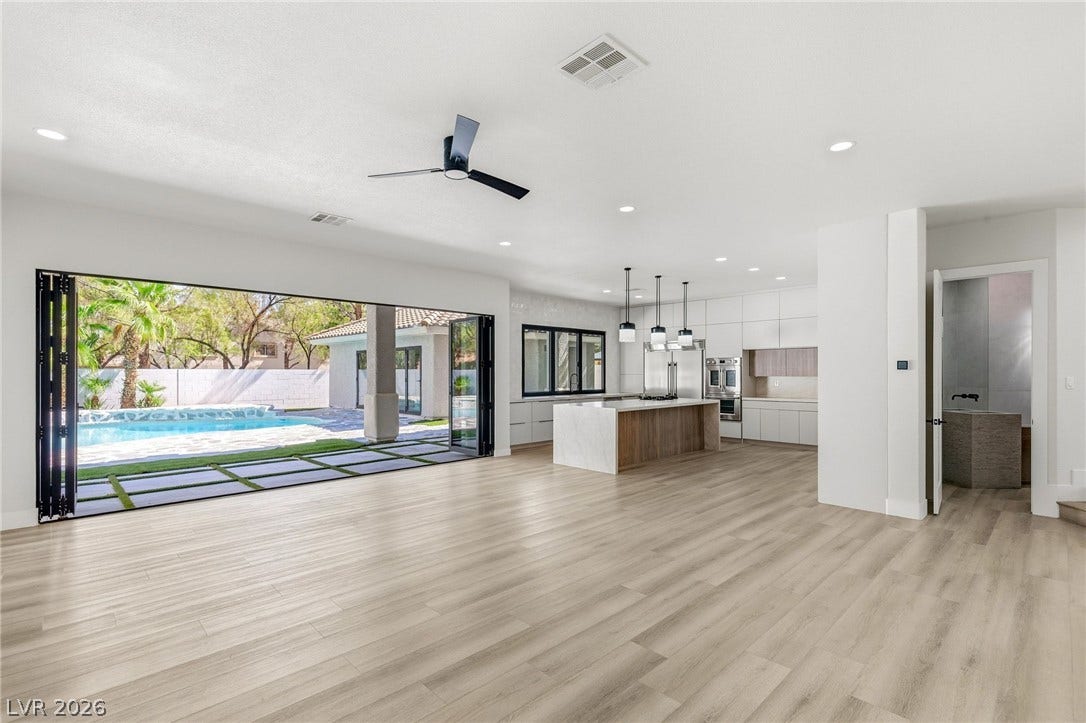 10626 San Vercelli Court, Las Vegas, NV 89141 Retractable glass doors seamlessly connect this airy open-concept living space to the pool deck.