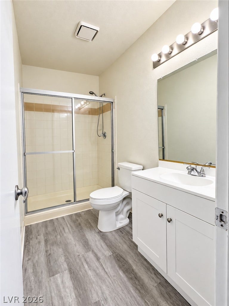 A classic layout with wood-look flooring and a walk-in shower with sliding glass doors.
