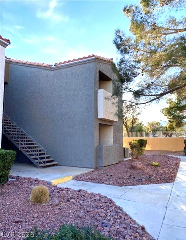 Concrete walkways lead past desert landscaping to the stucco exterior of this multi-level building.