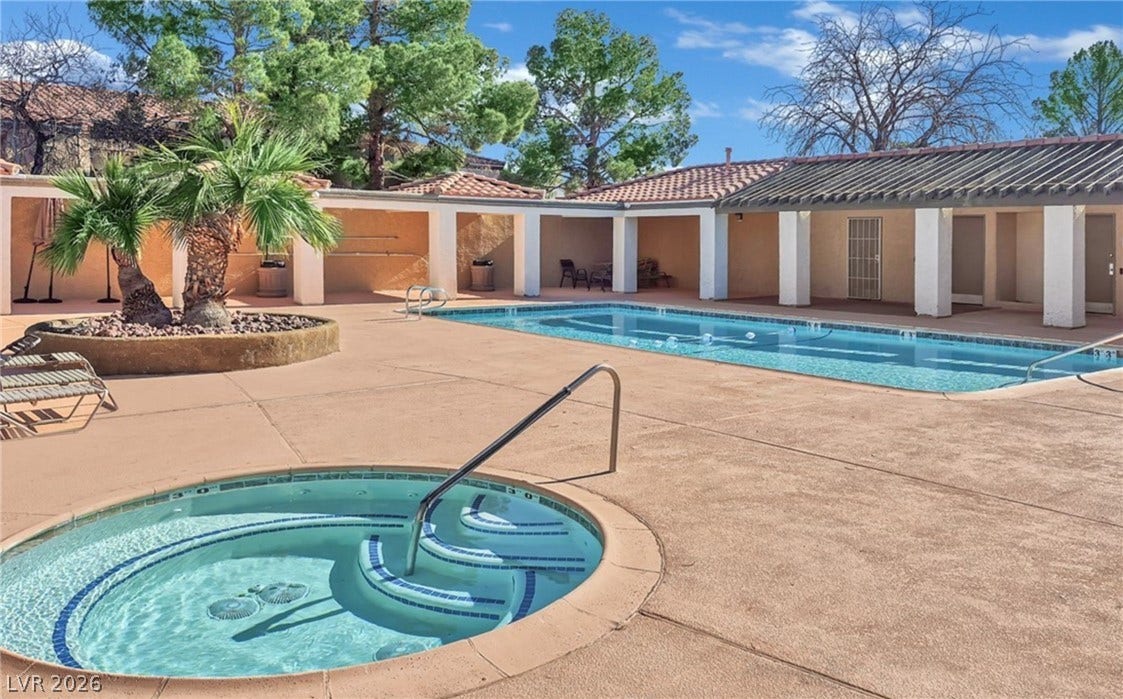 An inviting outdoor oasis with a swimming pool and integrated spa under clear skies.