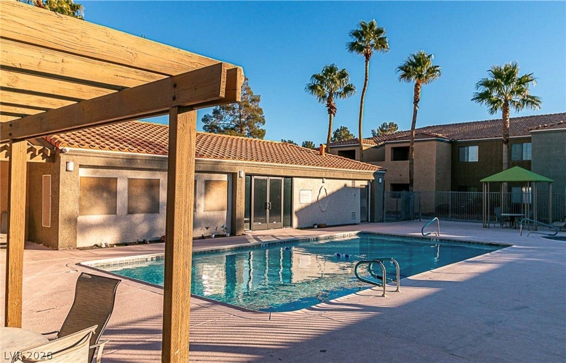 Palm trees sway over a sparkling pool surrounded by classic tile-roof architecture.