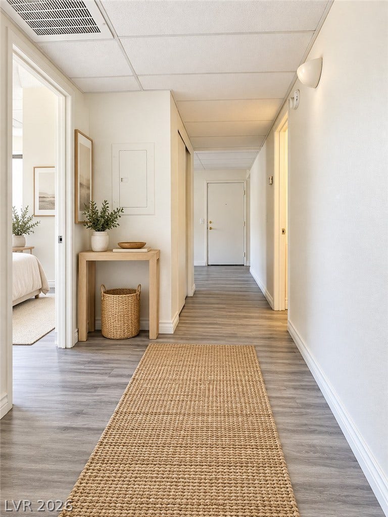 Virtually Staged Smooth wood-look flooring guides visitors through a welcoming and neutral entry hallway.