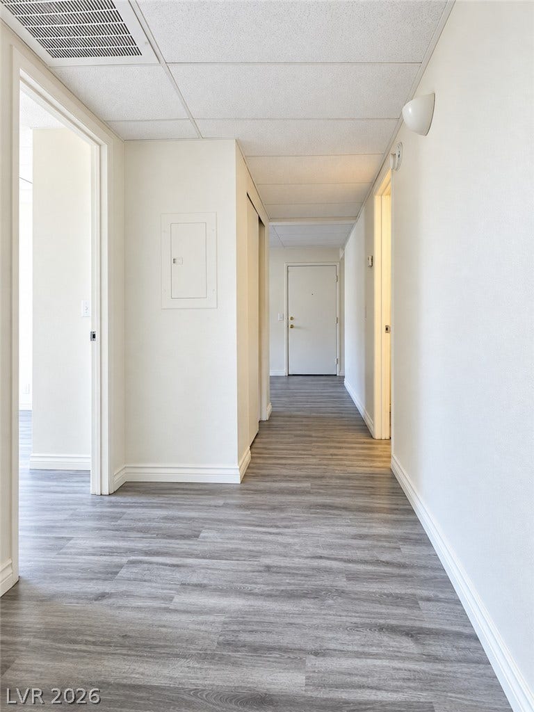 Smooth wood-style flooring runs continuously down this long, clean-lined interior hallway.
