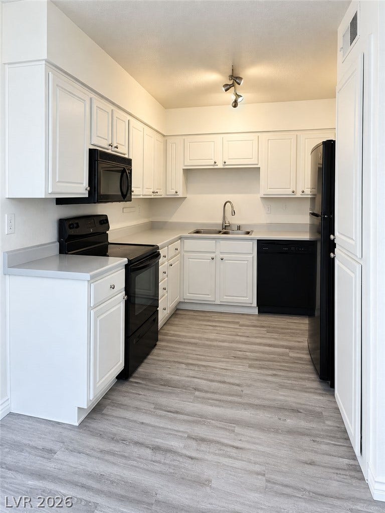 Crisp cabinetry contrasts with clean countertops and durable wood-look flooring in this functional layout.