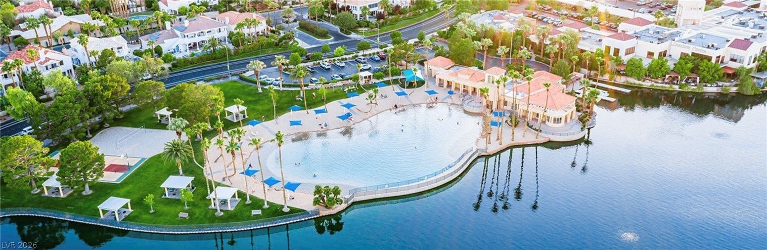 A spacious resort-style pool overlooks the calm blue waters of an adjacent private lake.