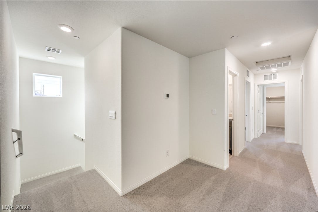 568 Ivory Peacock Ct, Henderson, NV 89011 Recessed lighting and soft carpeting create a welcoming ambiance throughout this upper-level hallway.