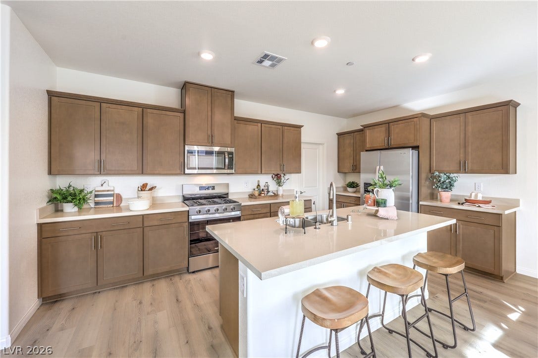 568 Ivory Peacock Ct, Henderson, NV 89011 A spacious island with built-in sink anchors this modern kitchen featuring recess lighting and wood flooring.