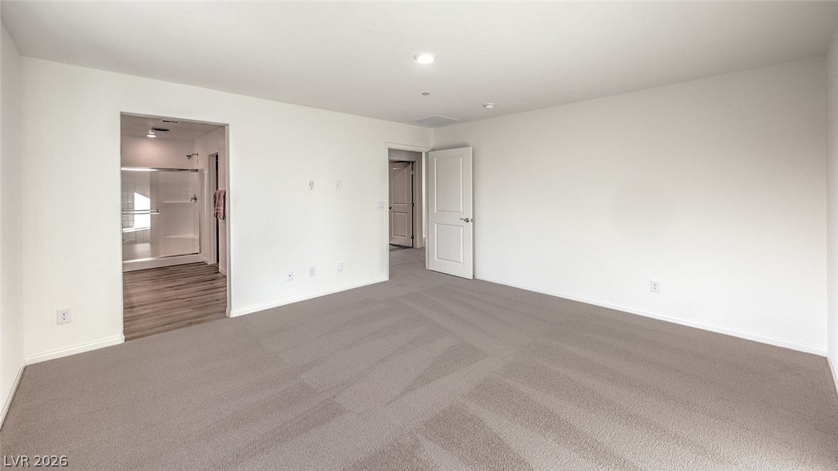 568 Ivory Peacock Ct, Henderson, NV 89011 Plush wall-to-wall carpeting and clean white walls anchor this quiet bedroom suite.