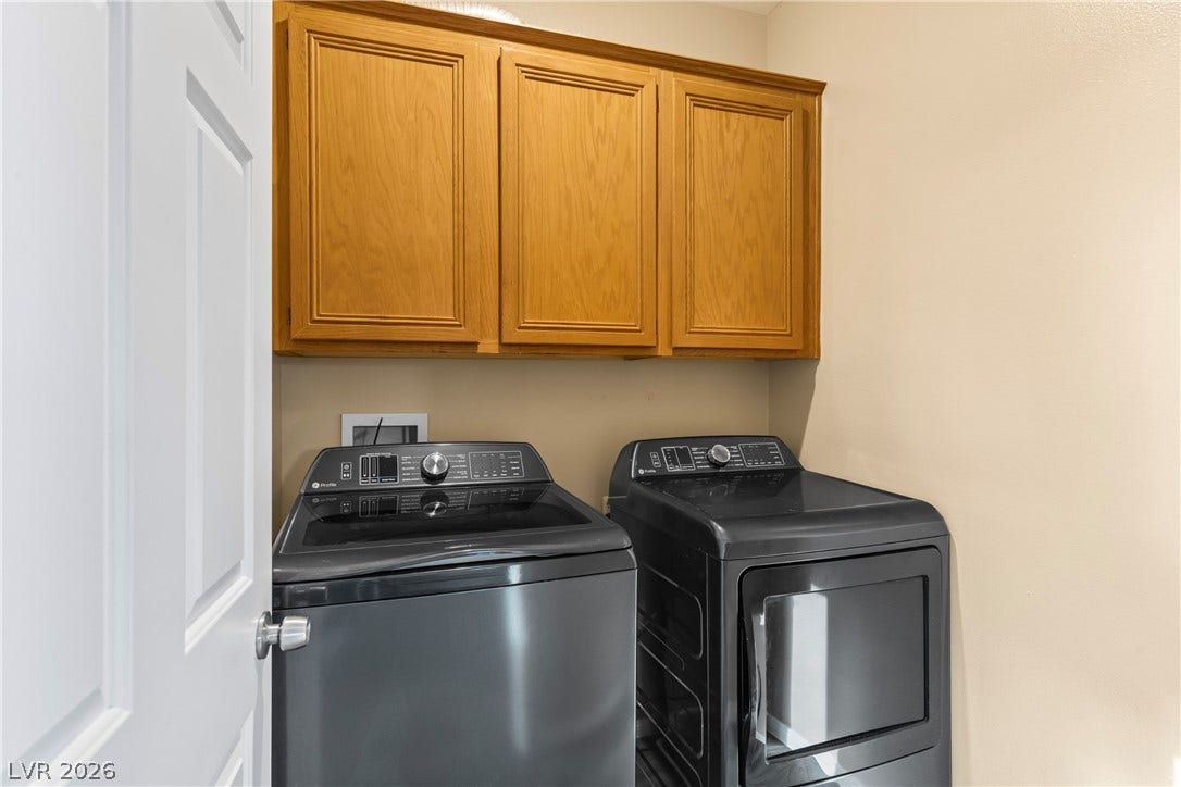 688 Canfield Point Avenue, Las Vegas, NV 89183 Functional cabinetry hangs above the washer and dryer setup in this dedicated laundry room.