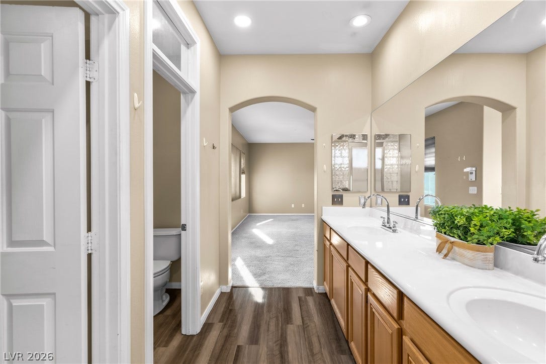 688 Canfield Point Avenue, Las Vegas, NV 89183 An arched doorway connects the long vanity bathroom to an adjacent carpeted suite.