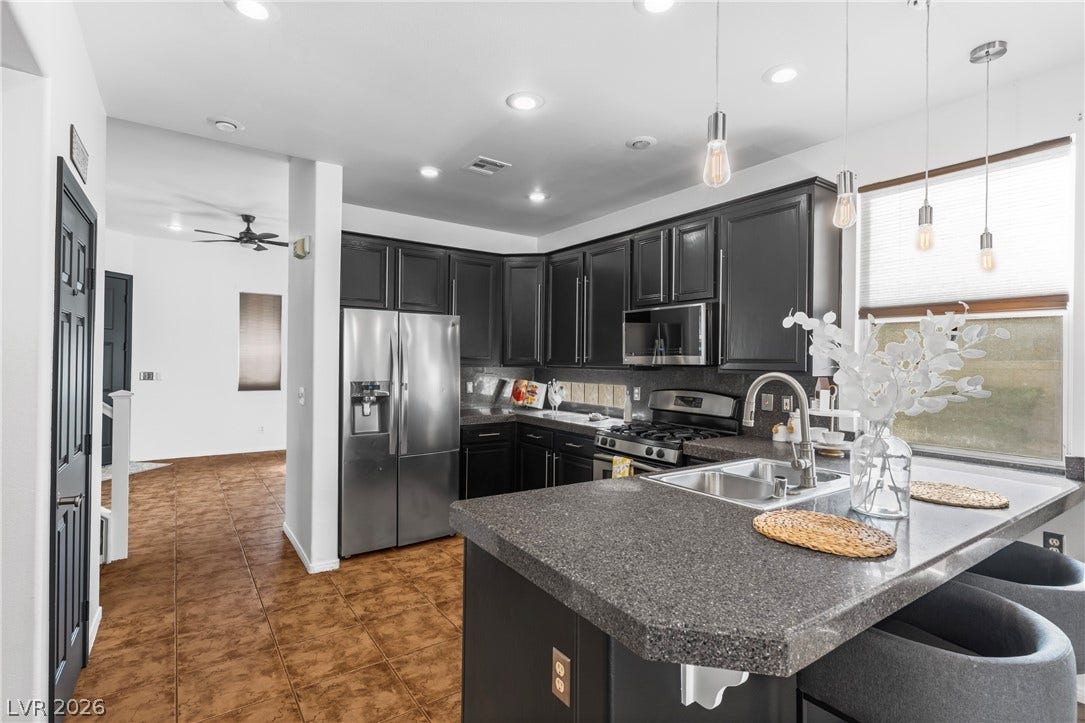 688 Canfield Point Avenue, Las Vegas, NV 89183 Dark cabinetry and solid stone counters define this modern kitchen with warm tile flooring.