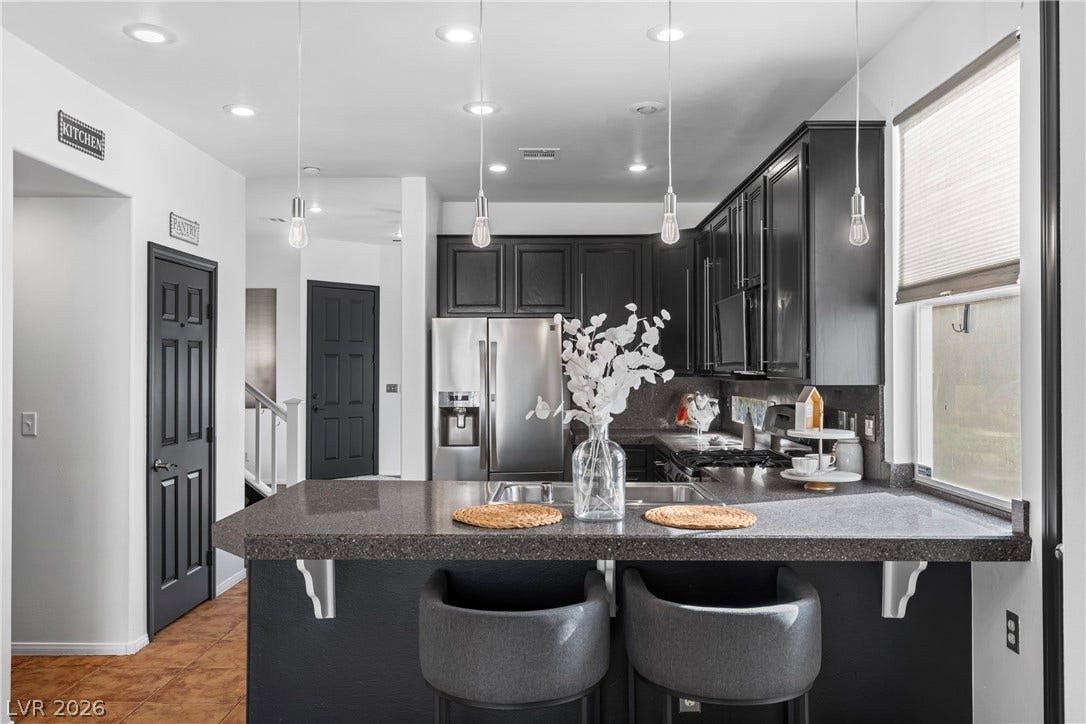 688 Canfield Point Avenue, Las Vegas, NV 89183 Dark cabinetry and solid stone counters elevate this contemporary cooking and dining space.