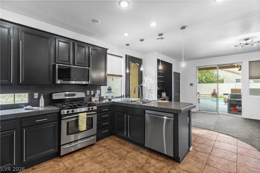 688 Canfield Point Avenue, Las Vegas, NV 89183 Dark cabinetry and tile flooring define this modern kitchen overlooking a backyard pool area.