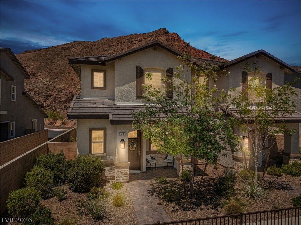 44 Kimberlite Drive, Henderson, NV 89011 This two-story residence features a charming entryway with stone accents and lush landscaping, with a lovely walking trail in front.