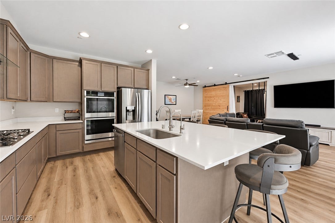 31 Cresta Villa Court, Henderson, NV 89011 Warm wood flooring and stone counters define this airy open-concept cooking and living space.