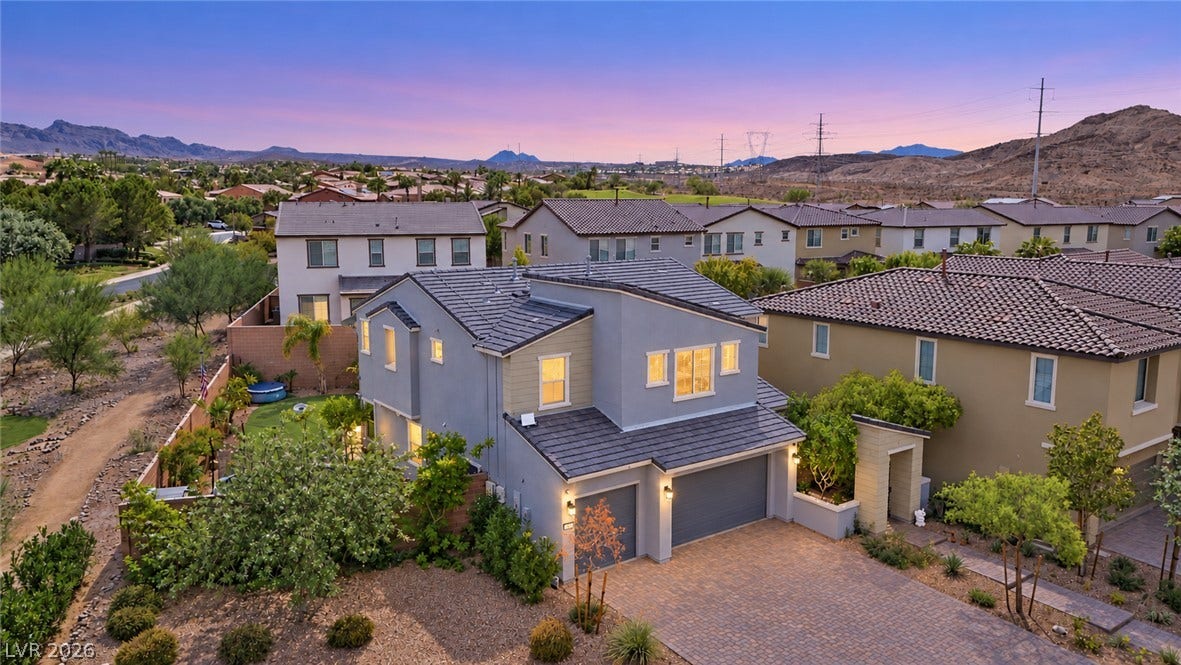 31 Cresta Villa Court, Henderson, NV 89011 Desert mountains rise behind this modern multi-level residence featuring a tile roof and paved driveway.