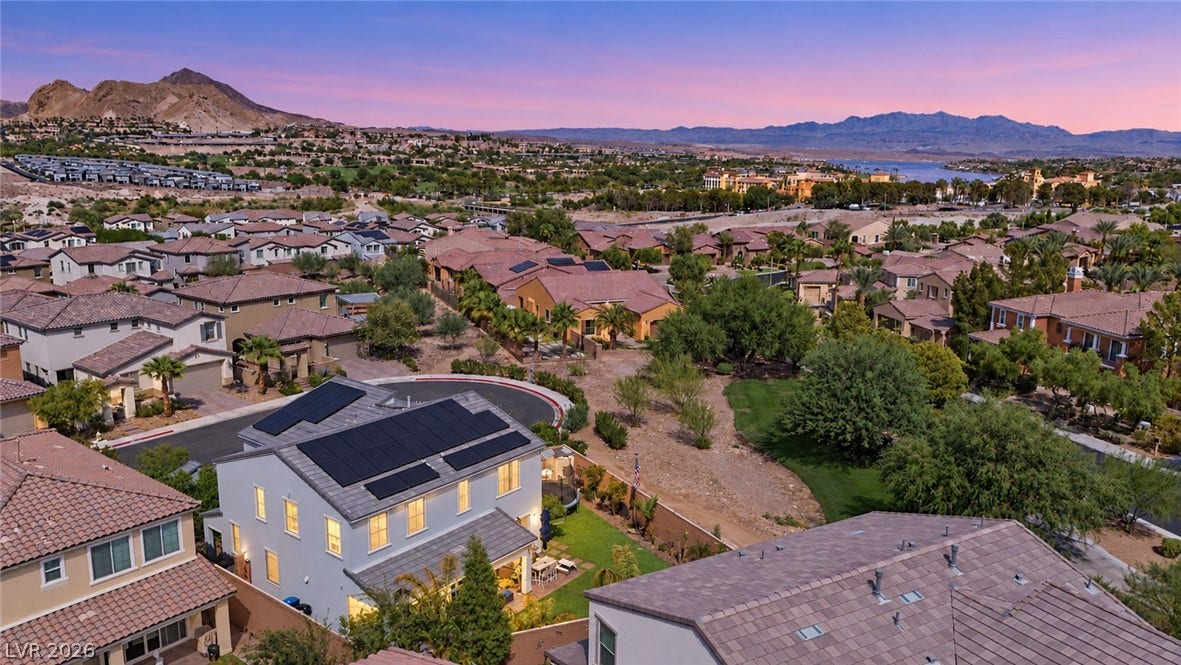 31 Cresta Villa Court, Henderson, NV 89011 Distant mountains frame a sprawling neighborhood under a vibrant sunset sky.