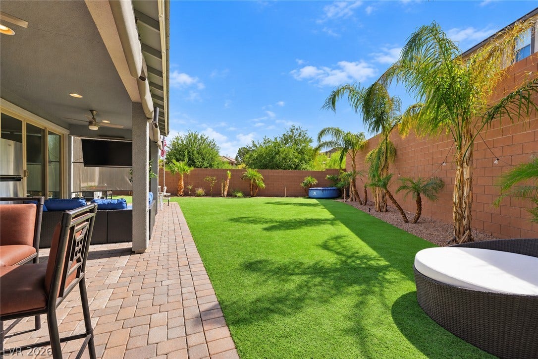 31 Cresta Villa Court, Henderson, NV 89011 A spacious block-walled backyard features lush green turf alongside a paved patio walkway.
