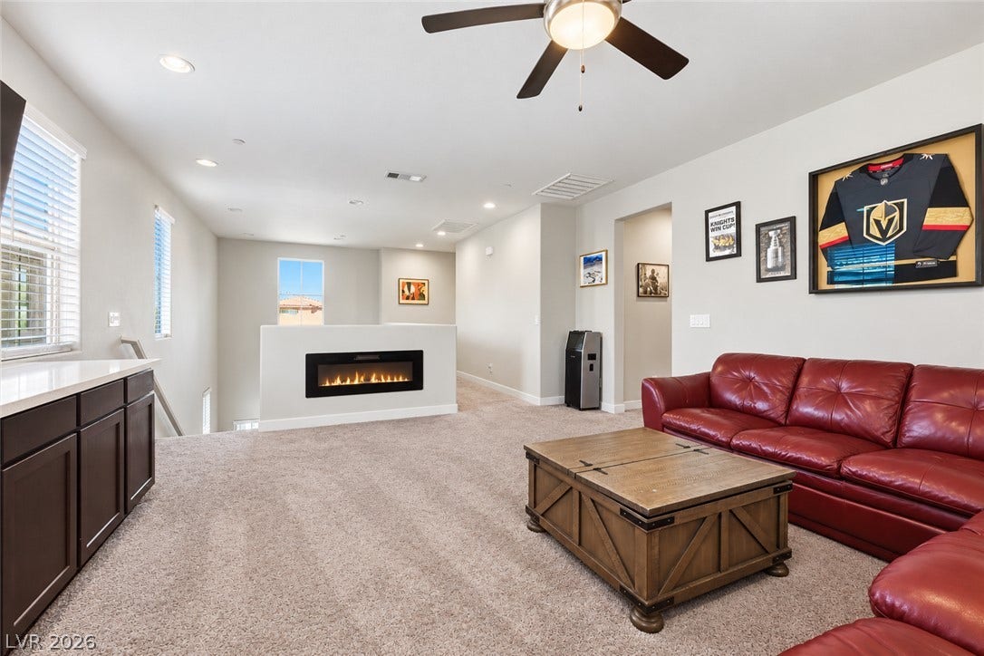 31 Cresta Villa Court, Henderson, NV 89011 An open upstairs living area features built-in cabinets, neutral carpeting, and a modern inset fireplace.