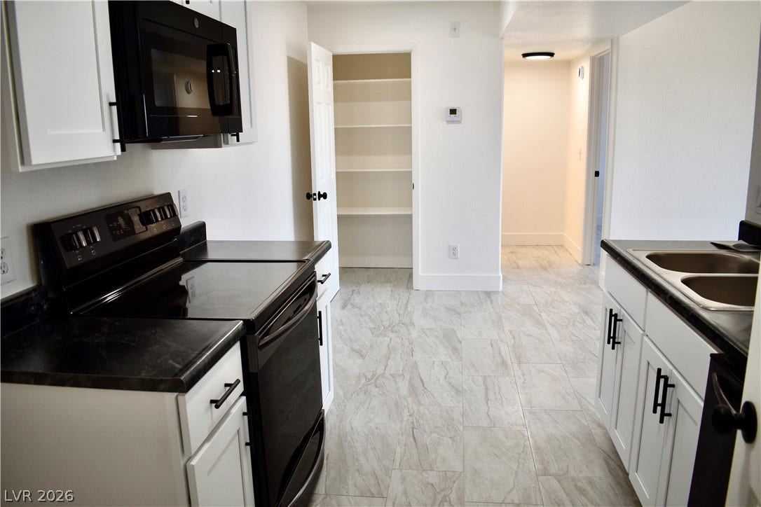 230 Mission Catalina Lane, #107, Las Vegas, NV 89107 An open doorway reveals built-in pantry shelves adjacent to modern kitchen cabinetry.
