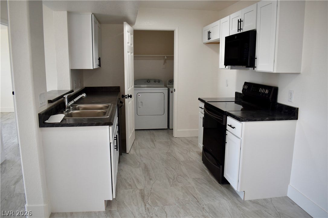 230 Mission Catalina Lane, #107, Las Vegas, NV 89107 Streamlined cabinetry and dark countertops flank durable tile-look flooring leading to an adjacent utility room.