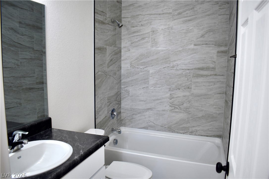 230 Mission Catalina Lane, #107, Las Vegas, NV 89107 Elegant stone look tile surrounds the bathtub in this modern bathroom setup.