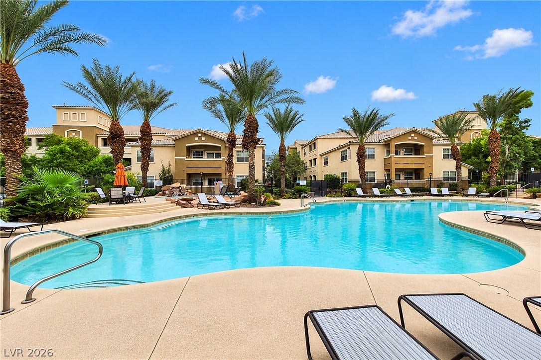 8777 W Maule Avenue, #2109, Las Vegas, NV 89148 Lush palm trees surround a resort-style swimming pool set against multi-story residential buildings.