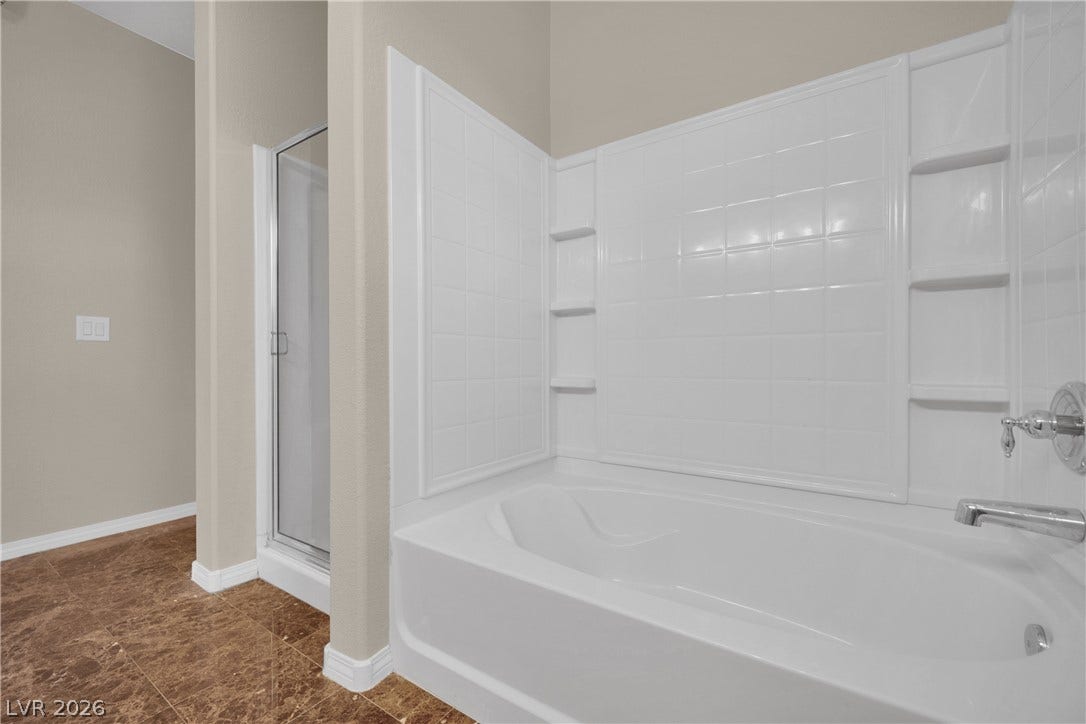 8777 W Maule Avenue, #2109, Las Vegas, NV 89148 An inviting soaking tub pairs with a separate glass-enclosed shower on polished tile flooring.