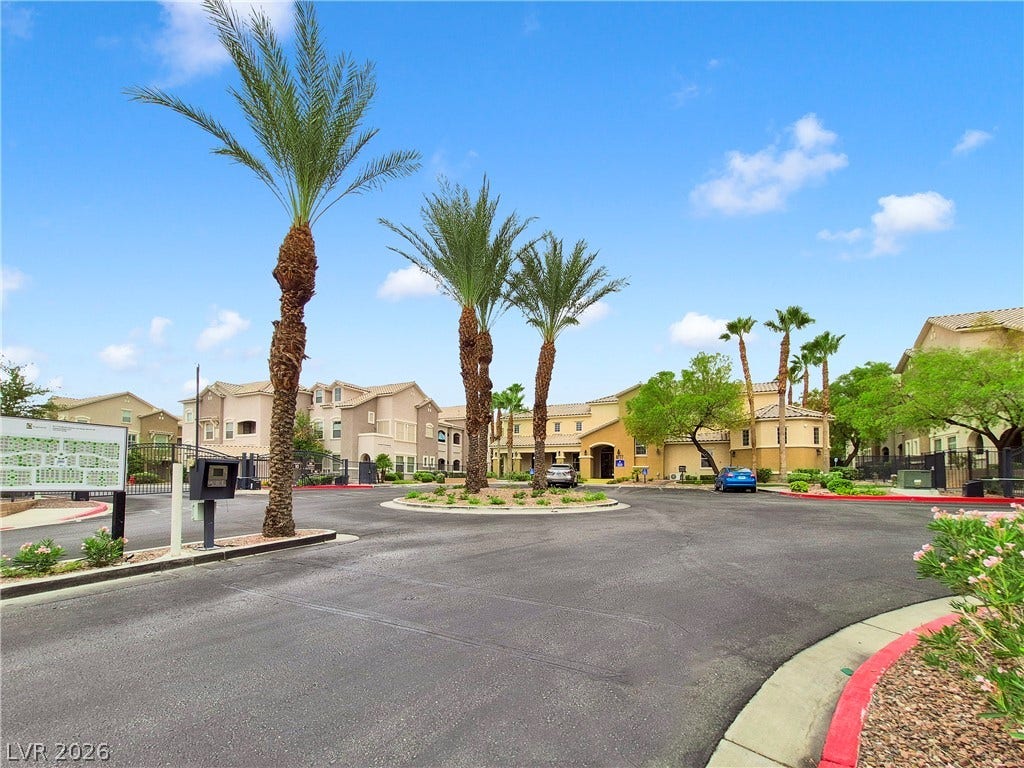 8777 W Maule Avenue, #2109, Las Vegas, NV 89148 Lush palm trees line the paved entry drive under a bright sky.