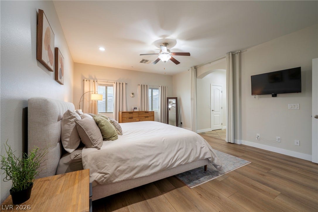 152 Dunblane Street, Henderson, NV 89012 Smooth wood-look flooring and an arched doorway anchor this serene and restful bedroom space.
