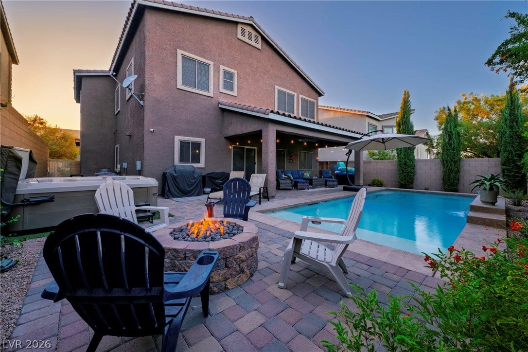 152 Dunblane Street, Henderson, NV 89012 An inviting backyard oasis features a shimmering pool, a stone fire pit, and paved patio spaces.