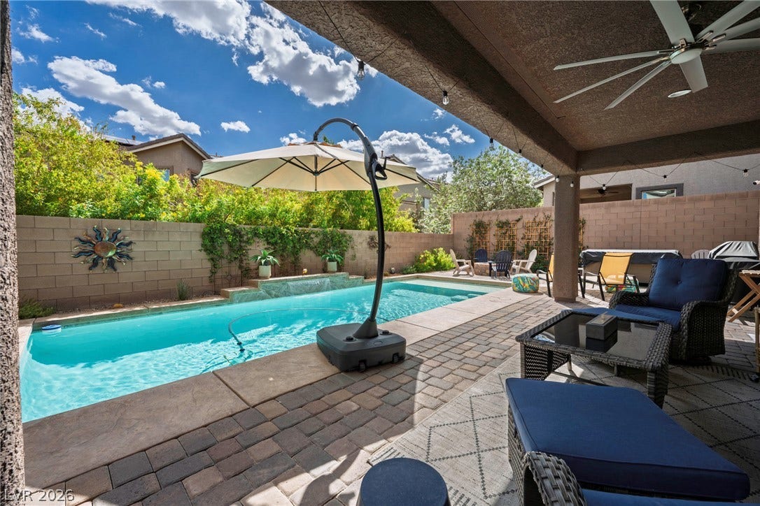152 Dunblane Street, Henderson, NV 89012 An inviting backyard oasis features a glistening swimming pool alongside a covered paver patio.