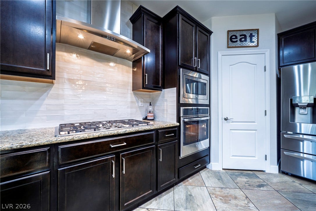 152 Dunblane Street, Henderson, NV 89012 Rich dark cabinetry and professional-grade appliances frame a beautifully tiled culinary workspace.