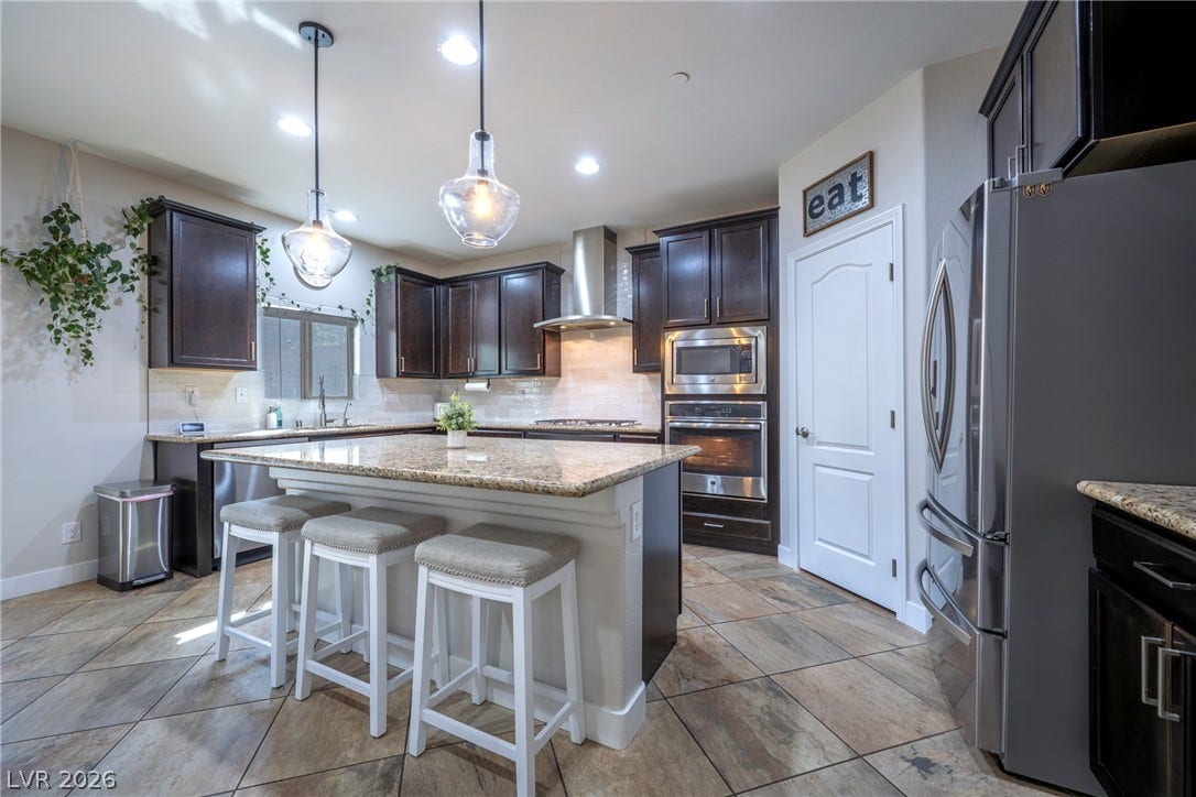 152 Dunblane Street, Henderson, NV 89012 Rich dark cabinetry and stone countertops anchor this functional kitchen workspace.