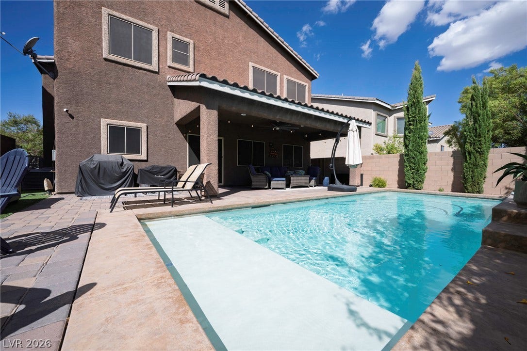 152 Dunblane Street, Henderson, NV 89012 An inviting backyard oasis features a sparkling in-ground pool alongside a spacious covered patio.