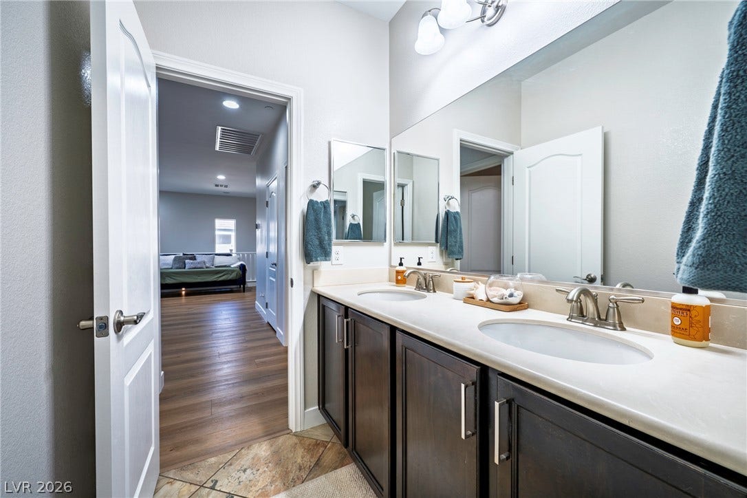 152 Dunblane Street, Henderson, NV 89012 A spacious double vanity features dark cabinetry and tiled flooring alongside a wide mirror.
