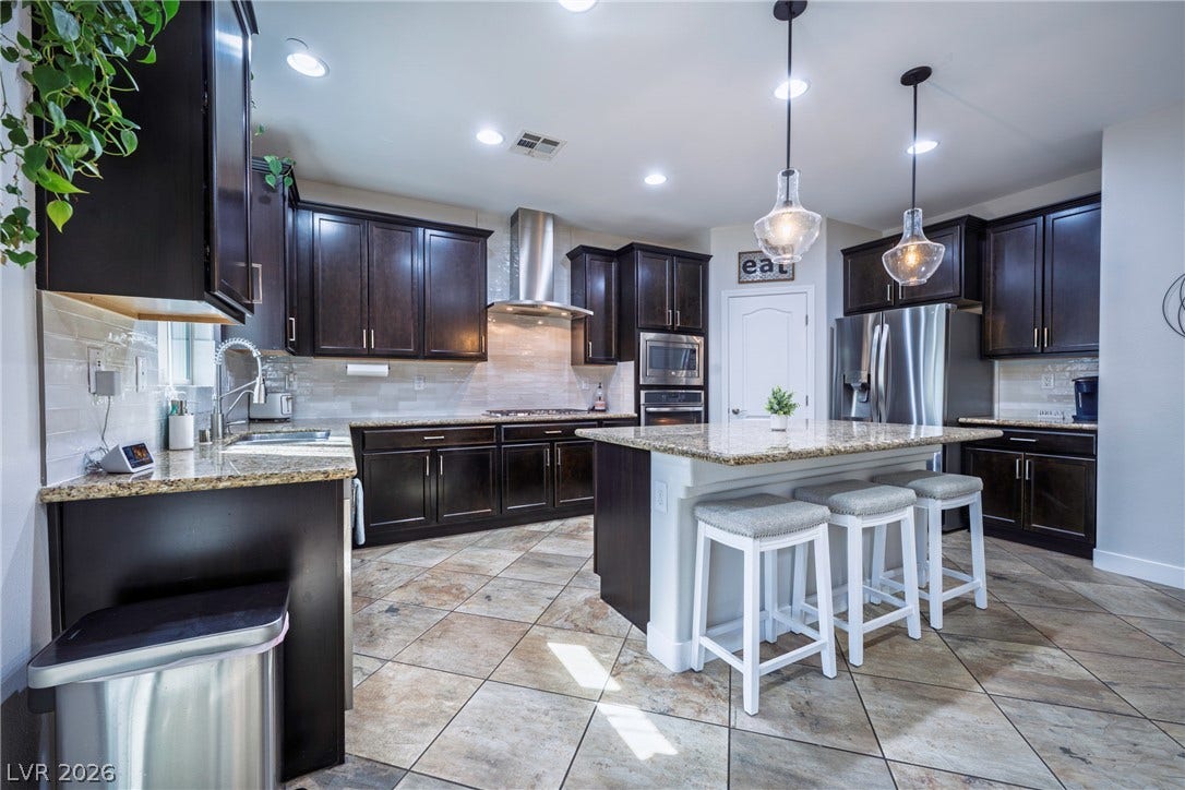 152 Dunblane Street, Henderson, NV 89012 Rich dark cabinetry pairs beautifully with stone countertops and a spacious central island.