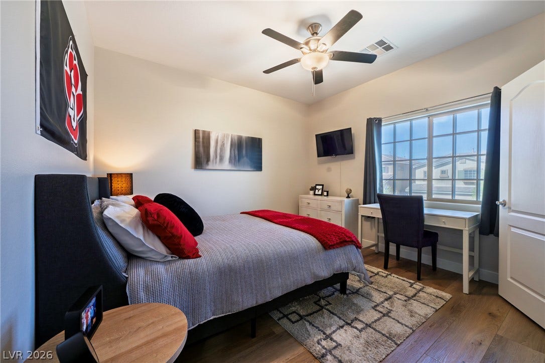 152 Dunblane Street, Henderson, NV 89012 A spacious bedroom features rich hardwood flooring and a large window offering neighborhood views.