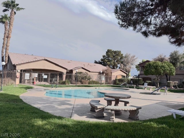 Mature trees frame the concrete pool decking and secure community swimming pool area.
