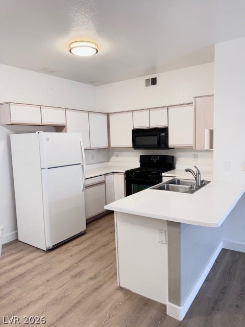 Smooth wood-look flooring anchors a functional culinary workspace designed with a convenient breakfast bar.