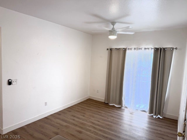 Smooth wood-look flooring with ceiling light/fan and a wide sliding glass door with drape, can access out to the balcony