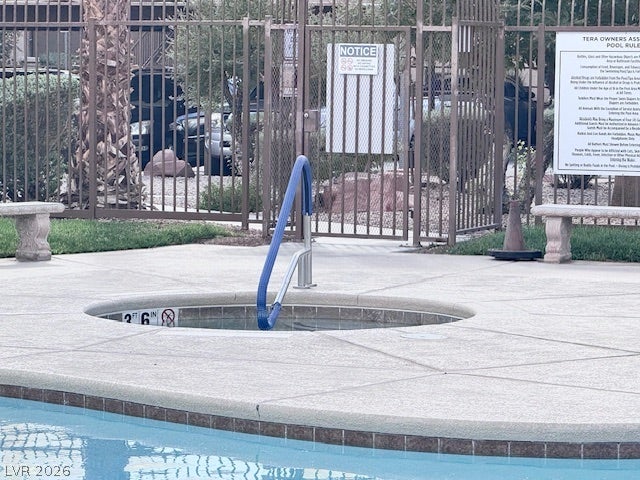 Secure fencing surrounds a well-maintained community spa and adjacent swimming pool area.