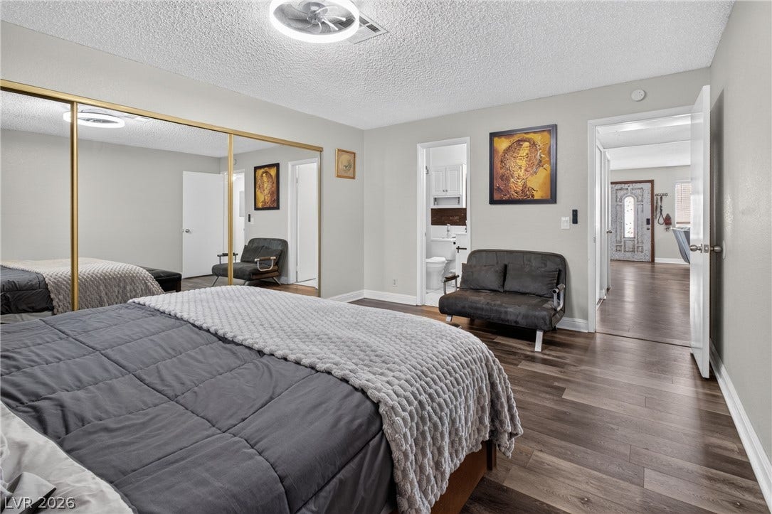 1341 Pinto Rock Lane, #202, Las Vegas, NV 89128 Rich wood-look flooring and integrated mirrored closet doors enhance this modern primary suite.