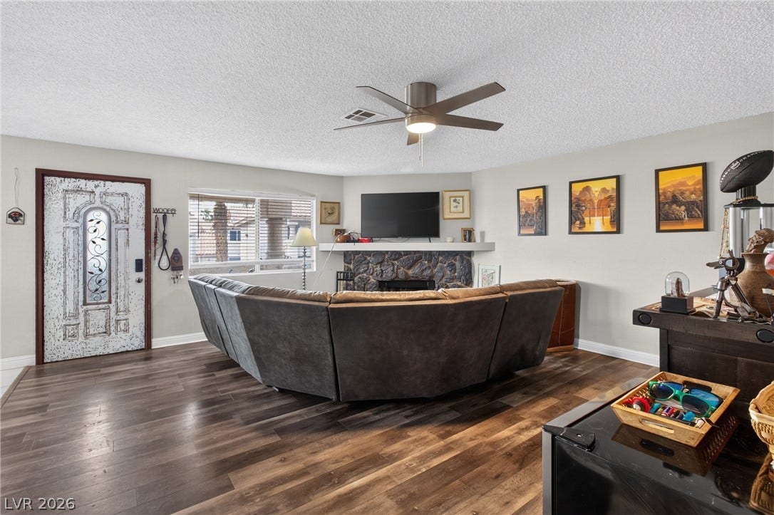 1341 Pinto Rock Lane, #202, Las Vegas, NV 89128 Rich wood-inspired floors and a classic stone fireplace anchor this welcoming open living space.