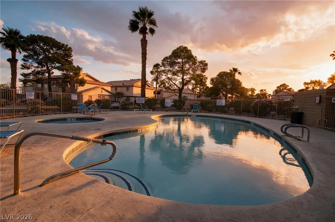 1341 Pinto Rock Lane, #202, Las Vegas, NV 89128 Mature palms and a concrete deck surround the sparkling community swimming pool at sunset.
