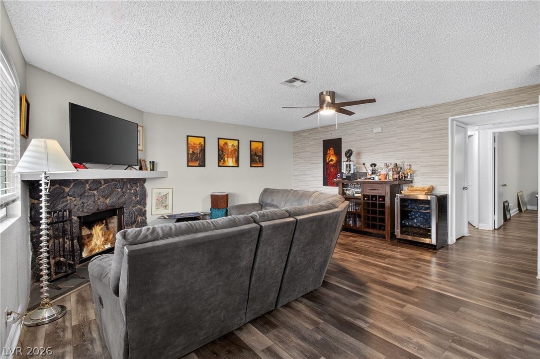 1341 Pinto Rock Lane, #202, Las Vegas, NV 89128 Rich wood flooring pairs beautifully with a textured stone fireplace in this comfortable living area.