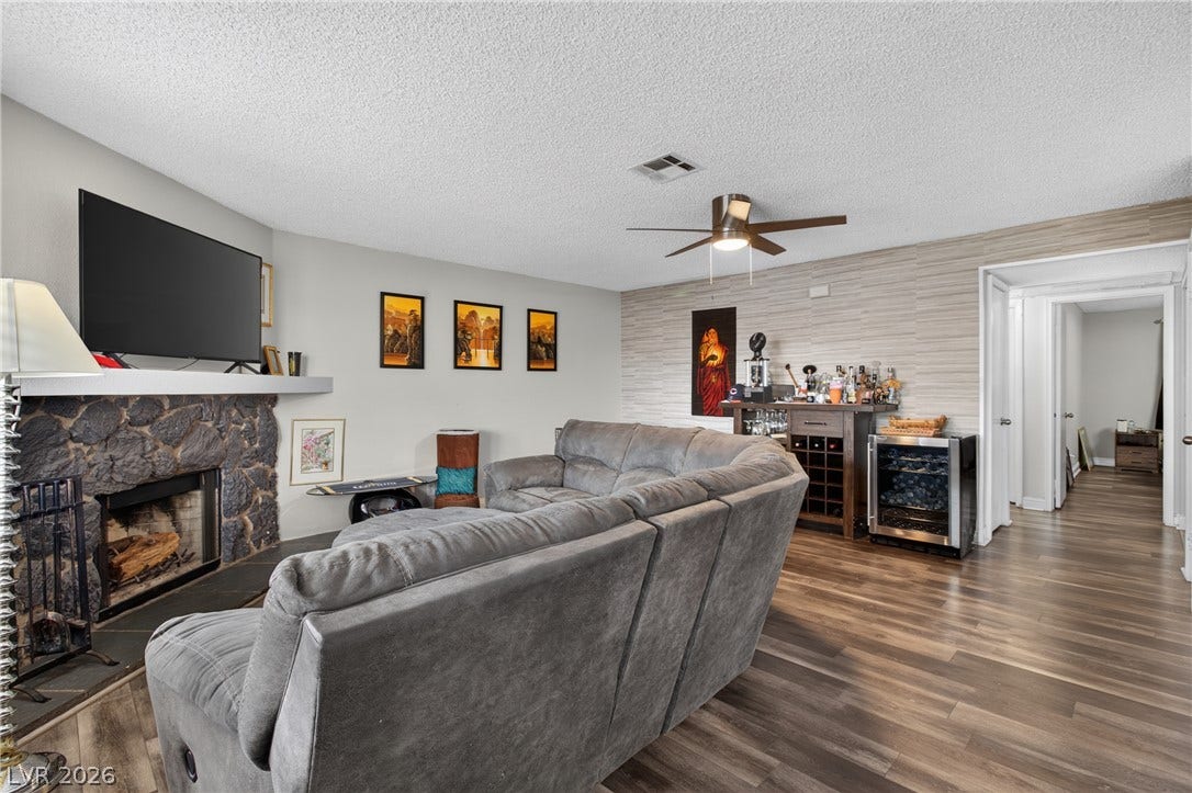 1341 Pinto Rock Lane, #202, Las Vegas, NV 89128 Rich wood-look flooring and a rugged stone fireplace anchor this inviting living space.